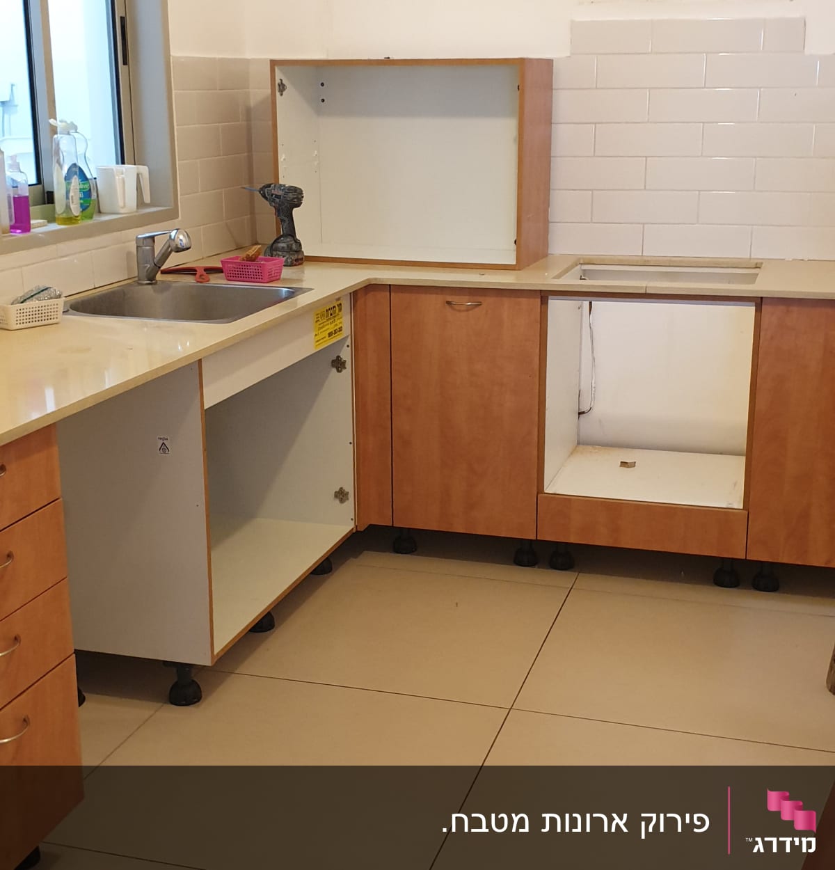 מטבח בשיפוץ עם ארונות פתוחים ומקדחה על השיש